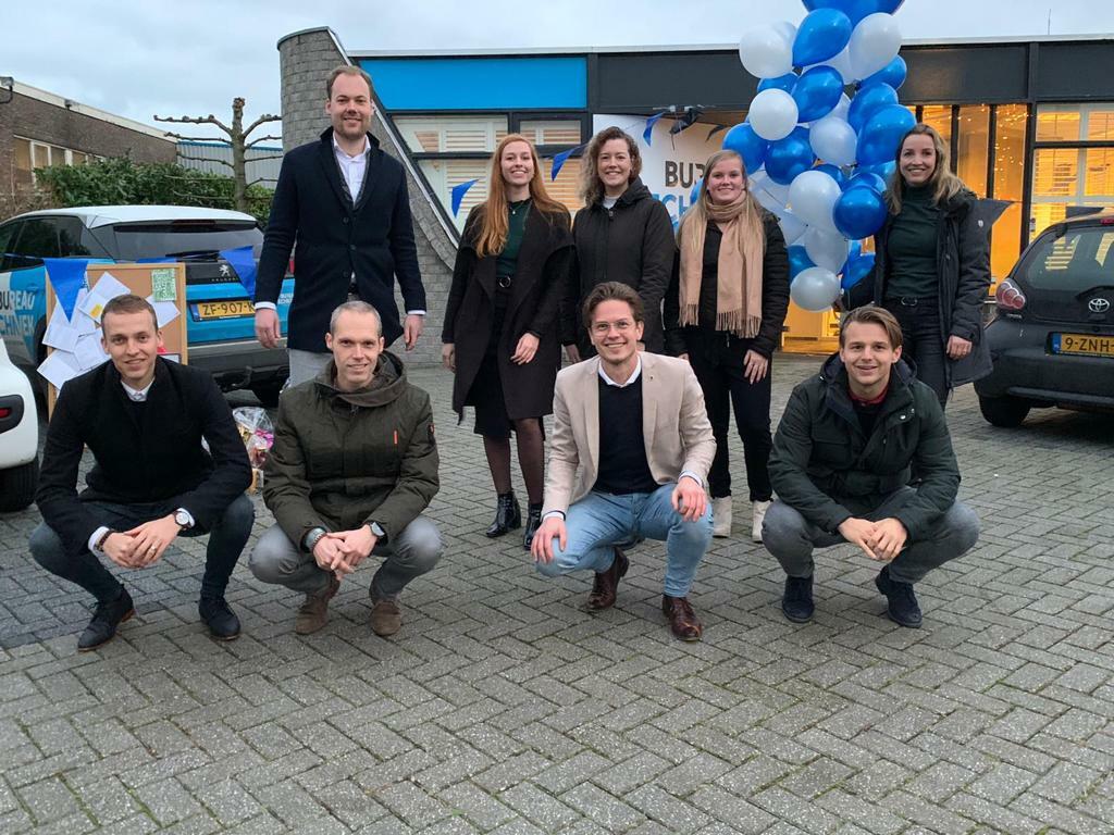 Groepsfoto van het team voor het pand