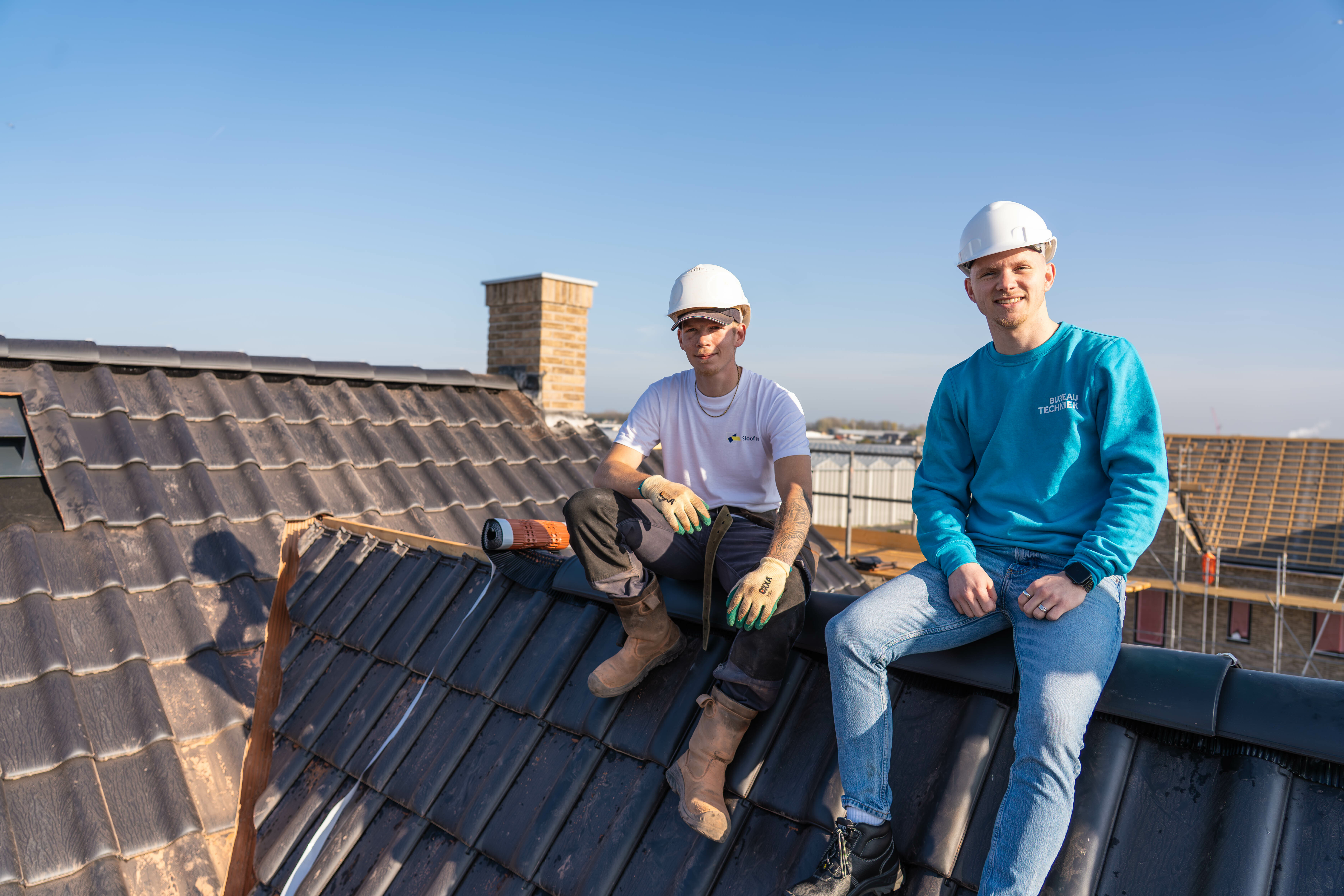 Twee collega's met helm op een dak